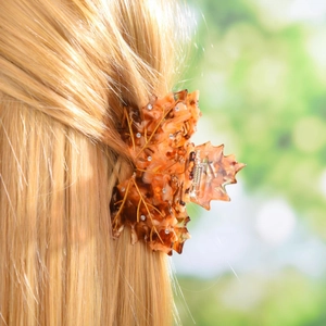 Macro shot of maple leaf hair claw with tortoise pattern and rhinestones in golden hair