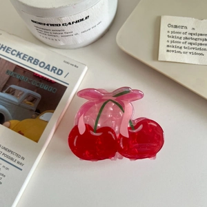 Detailed view of a cherry-shaped hair claw with pink bow and translucent red finish