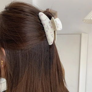 Pince à cheveux fleurie avec strass présentée sur cheveux longs dans un décor clair