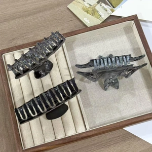 Close-up of three acetate bat and marble pattern hair claws on a wooden display tray
