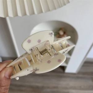 Détail d'une grande pince à cheveux crème avec motifs floraux violets et nœuds