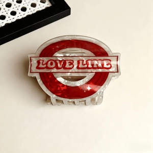 Detail view of acetate claw clip with marble texture and red Love Line emblem design