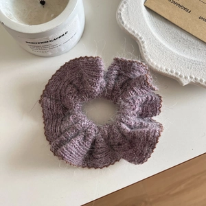 Detail of lilac knitted scrunchie with brown wavy lace edges on a clean white desk
