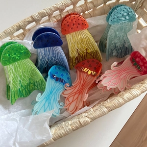 Colorful translucent jellyfish hair claws in a woven basket with oceanic patterns