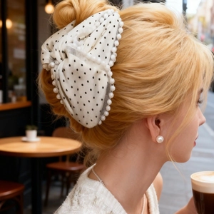 Close-up of a French style large pearl polka dot bow hair claw clip worn on a bun