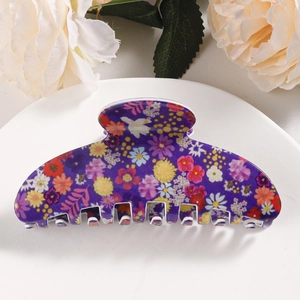 Detailed view of dark purple floral hair claw clip on a white decorative display plate