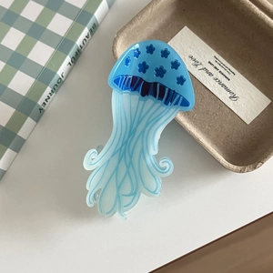 Detailed view of the blue jellyfish acrylic hair claw with floral pattern on white desk