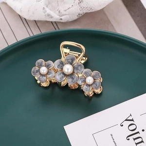 Detailed shot of golden flower hair claw with grey marble petals and white pearls