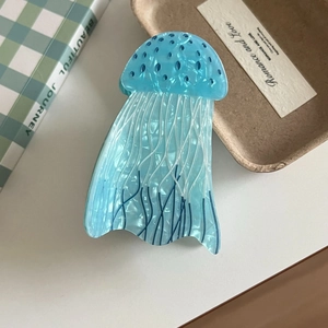 Detail of creative blue jellyfish hair claw clip made of pearlescent acrylic on a desk