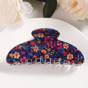Detail of floral hair claw clip with colorful daisy pattern on a glossy dark base