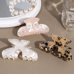 Three elegant acetate hair claw clips with rhinestones in pink, white, and tortoiseshell