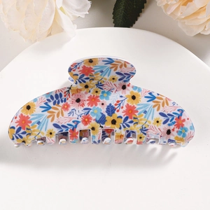 Detailed view of a floral hair claw clip with colorful daisy pattern on a white tray
