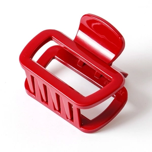Detail of a bright red square hair claw clip made of shiny resin with durable teeth
