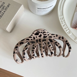 Macro di una grande molletta per capelli leopardata su un tavolo da toeletta bianco elegante