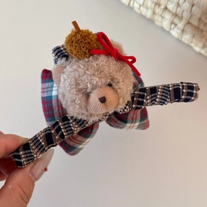 Detail of cute plush bear hair claw clip featuring a red bow and a knitted hat