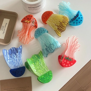 Colorful jellyfish-shaped acrylic hair claws in multiple colors on a white table