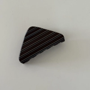 Detail of a minimalist triangular hair claw clip with black and white horizontal stripes