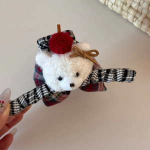Detailed view of cute plush bear hair claw with tartan plaid fabric and festive red bow