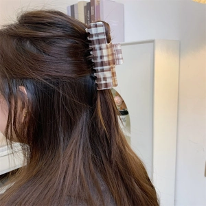 Detailed side view of a large vintage checkered acetate hair claw clip worn in hair