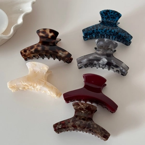 Minimalist acetate hair claws set in tortoiseshell and marble patterns on white surface