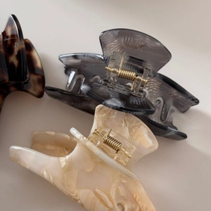 Detailed macro view of three acetate hair claws in tortoiseshell, gray, and cream marble