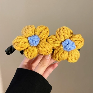 Vue détaillée de la pince à cheveux fleurs jaunes au crochet avec centres bleus tricotés