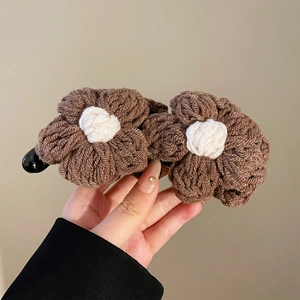 Détail de fleurs au crochet marron et crème sur une pince à cheveux banane noire brillante