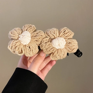 Gros plan sur une pince à cheveux fleurs tricotées beige avec texture en laine