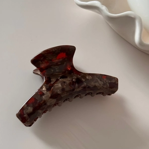 Detail view of tortoiseshell acetate claw clip showing polished amber pattern and teeth