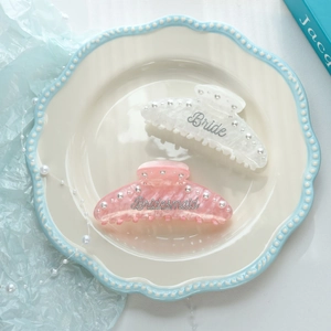 Detail of Bride and Bridesmaid pearl hair claws on a ceramic tray with elegant decor
