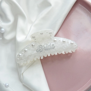 Detail view of acrylic hair claw with white marble texture and Bride pearl embellishment
