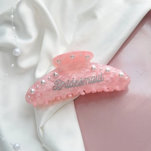 Detailed view of pink marble hair claw clip with Bridesmaid silver lettering and pearls
