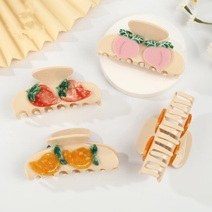 Detail of cream hair clips with 3D strawberry and peach patterns on a display stand