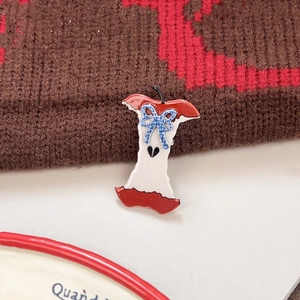 Detail of apple core enamel pin with blue plaid bow on warm knit texture