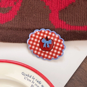 Close-up of red and white plaid apple hair clip with blue bow and wavy edges