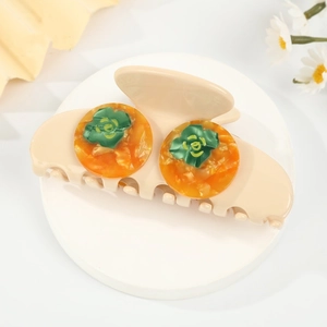 Close-up of beige acetic hair claw clip with amber orange circular floral accents