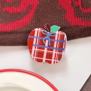 Detailed close-up of apple-shaped acetate hair clip with red and white plaid pattern