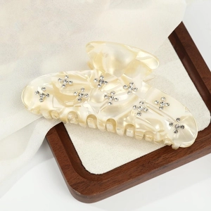Macro detail of cream acetate hair claw clip with star rhinestones on wooden background