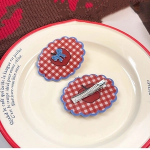 Retro red and white plaid hair clips with cute apple and bow design on ceramic plate