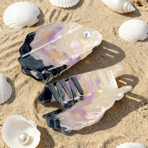Acetate shark hair clips with pearls and colorful marble pattern on beach sand