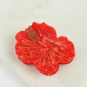 Detail of red hibiscus hair claw clip with golden stamen and acetate petal texture