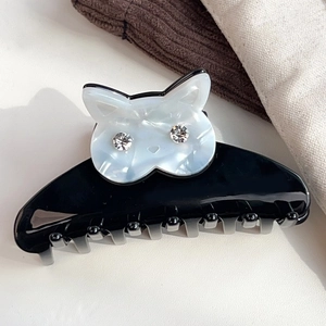 Détail d'une grande pince à cheveux noire en acétate avec chat à texture nacrée et strass