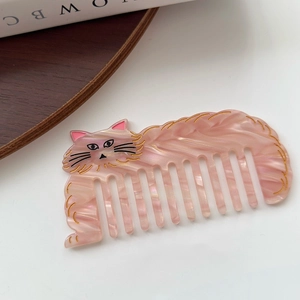 Vue détaillée du peigne en acétate marbré rose en forme de chat avec des détails dorés