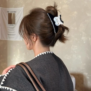Détail d'une pince à cheveux en acétate noir avec fleurs en nacre portée par un modèle