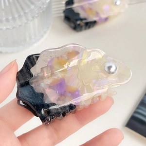 Detailed close-up of iridescent acetate hair claw clip with a decorative grey pearl