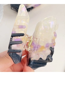 Detail view of acetate butterfly hair claw with pearlescent purple marble finish and gold spring