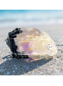 Detailed macro shot of a pearlescent acetate rabbit shaped hair claw on beach sand