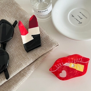 Creative acetate hair claw clip set with red lip and lipstick designs in a fashion setting