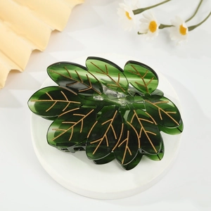 Vue détaillée d'une pince à cheveux feuille vert foncé avec des nervures dorées