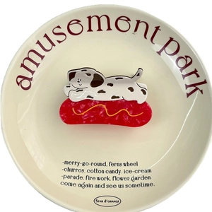 Pince à cheveux dalmatien hot-dog en acétate sur une assiette décorative en céramique